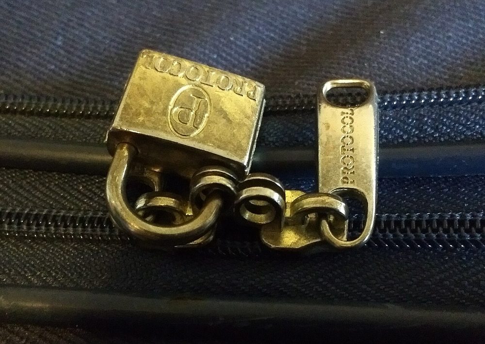 A brass padlock on the zip of a suitcase